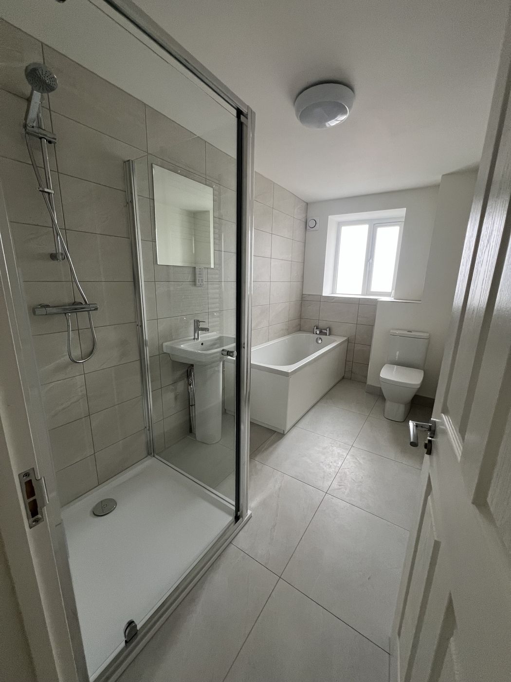 Finished bathroom with glass shower enclosure, basin, bath and toilet