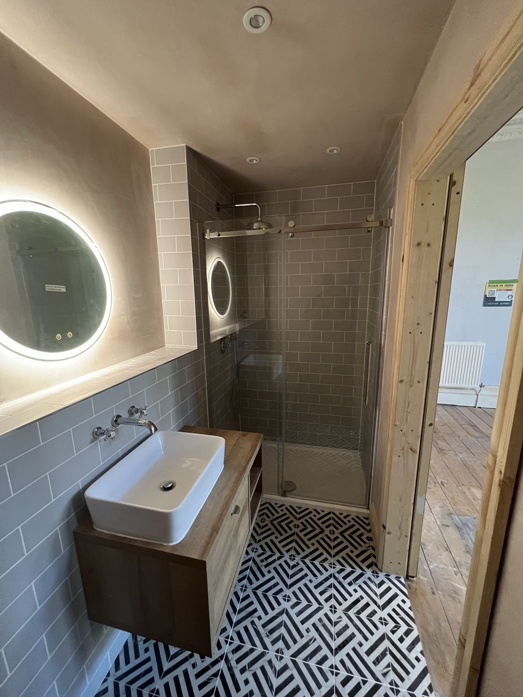 Finished bathroom with grey metro tiles, patterned floor and wall-hung vanity