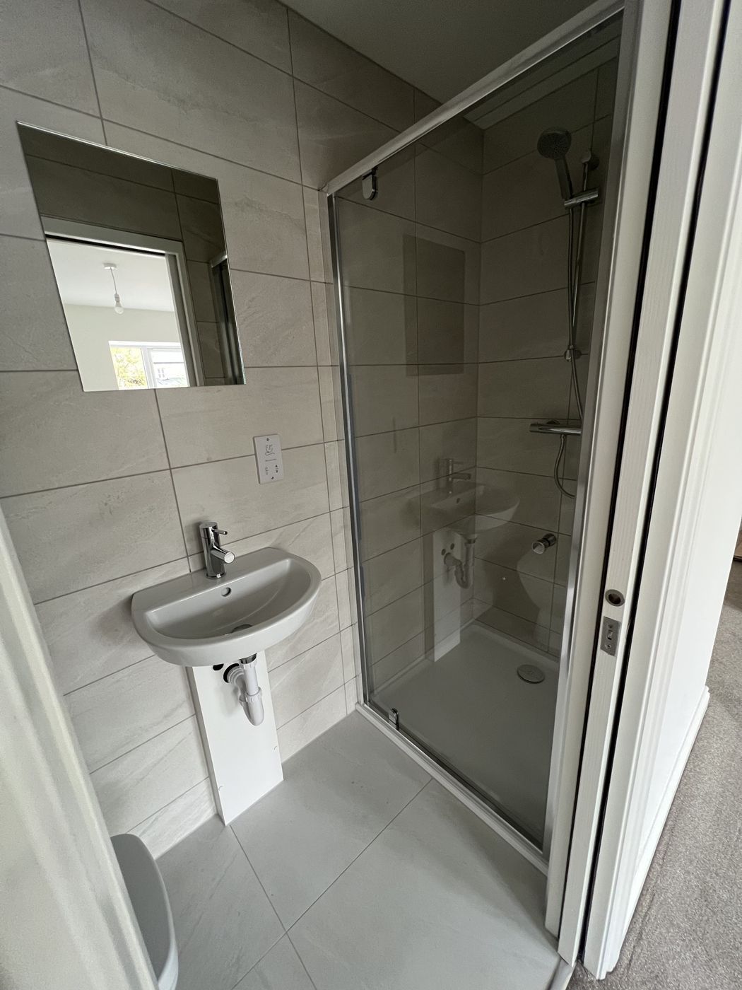 Finished shower room with basin, mirror and glass shower enclosure