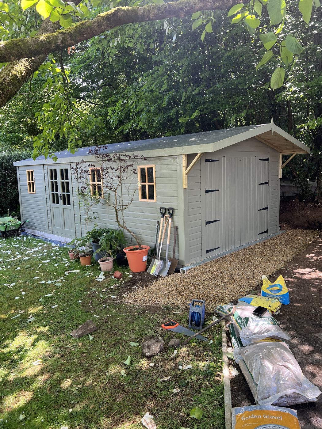 Completed painted prefab shed with double doors and gravel path
