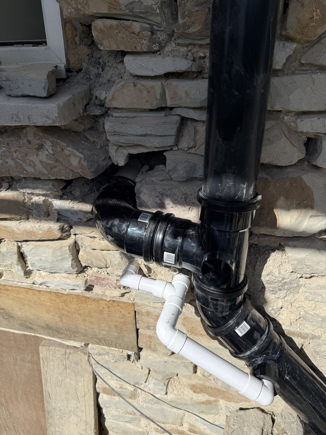 New soil stack with fresh junctions on a stone wall