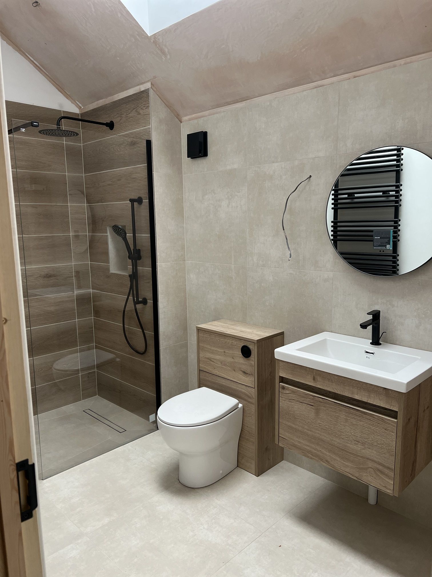 Finished walk-in shower room with wood-effect tiles, black fittings and a floating oak vanity